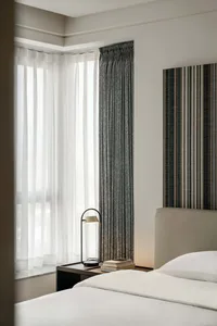 A modern bedroom featuring grey and white fabric curtains