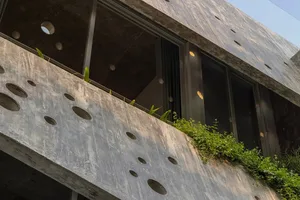 Concrete building exterior with round cutouts and green plants