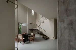 A modern interior featuring concrete floating stairs and minimalist furniture.