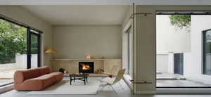 Modern living room with a fireplace, minimalistic furniture, and visible exterior wall