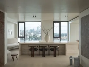 Modern living area featuring a marble counter with concrete stools and a vase of branches.