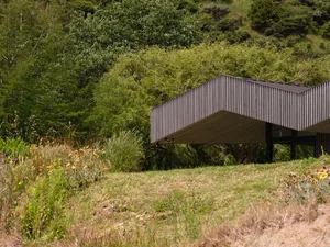 A modern building with a metallic exterior surrounded by greenery.