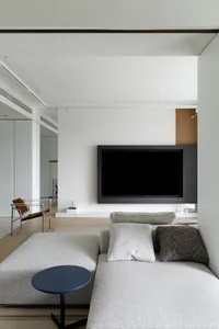 Modern minimalist living room with grey fabric sofa, black coffee table, and black TV on the wall.