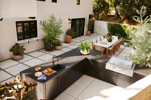 An overhead view of a modern outdoor kitchen with metal cabinets, stone countertops, and a stainless steel grill.