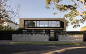 Modern residential exterior with large wooden panels and large glass windows.
