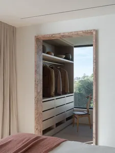 Modern wardrobe with marble and wooden elements, featuring a view of greenery.