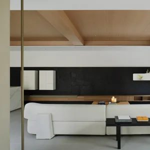 A modern living room featuring a white sofa and black backwall.