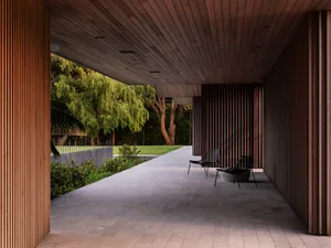 Modern patio featuring wooden curtains and black chairs with lush greenery.