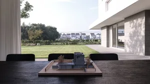 A model of a building with a modern design, set against a backdrop of a well-maintained lawn and residential houses.