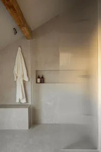A minimalist bathroom with glass walls and a wooden beam on the ceiling.