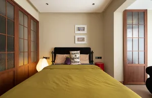 A minimalist bedroom with a yellow bed, black and white pillows, and a black headboard.