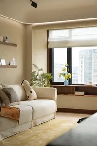 A modern minimalist living room with a white sofa, green plants, and a large window.