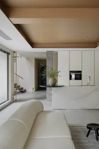 Modern minimalist living room with marble accent wall, white sofa, and black accents.