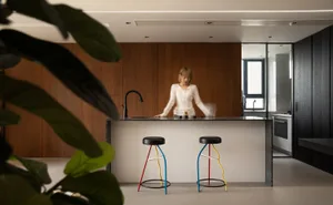 A modern, minimalist residential kitchen featuring a concrete countertop and wooden cabinetry.