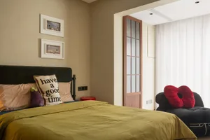 A modern bedroom featuring a comfortable bed with a pillow, eggs, and a red beanbag, and a cozy lounge area with a chaise lou