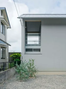 Modern residential house with concrete cladding exterior, small garden area with gravel and greenery, and minimalist architec