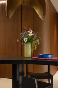 A modern dining room featuring a wooden table adorned with a vase of fresh flowers.