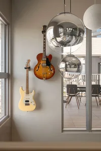 A modern living room featuring a hanging electric guitar, a hanging electric guitar in a semi-hollow body style, and a hangin