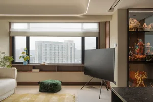 A modern living room with a concrete floor, a white couch, and a large window overlooking a cityscape.
