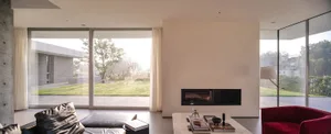 Modern living room featuring glass walls, concrete floor, and steel furniture.