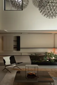A modern living room with minimalist design featuring neutral tones and a large indoor plant.