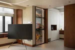 A modern living room with an open-concept design, featuring a large screen TV, a display cabinet showcasing collectible figur