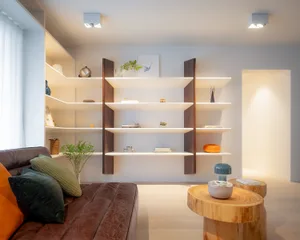 A modern living room with white shelves and wood details, featuring a brown leather sofa and a wooden coffee table.
