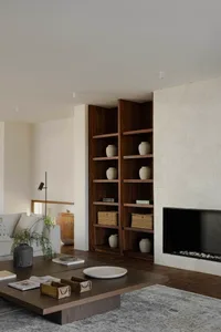Modern living room with wooden shelves, ceramic vases, and stone fireplace