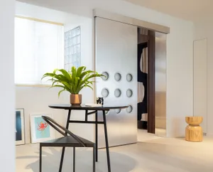Modern living room featuring a sleek, metallic accent wall with glass-enclosed shelving and wooden furniture.