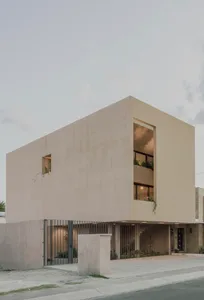 A minimalist modern residential exterior with concrete walls, large windows, and a small balcony.