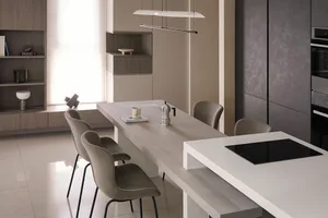 A modern minimalist kitchen with wooden countertops, stainless steel appliances, and a long island with a built-in cooktop an