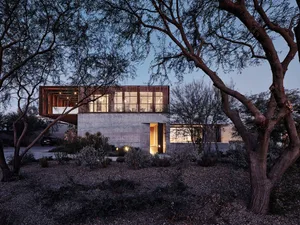 A modern residential architecture featuring a combination of concrete and wood materials with a glass facade.