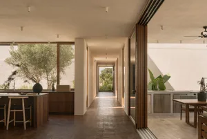 Modern residential interior design featuring wooden finishes, terracotta flooring, and large glass windows.