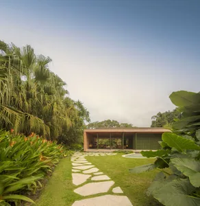A modern residential exterior with a stone pathway and tropical garden.