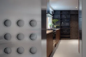 Modern kitchen featuring industrial-style metal shelves with round cutouts, wooden cabinets, and glass elements.