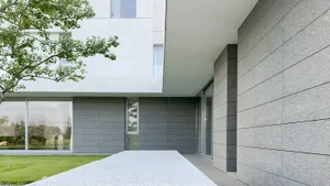 A modern minimalist entryway with a concrete wall and large windows.