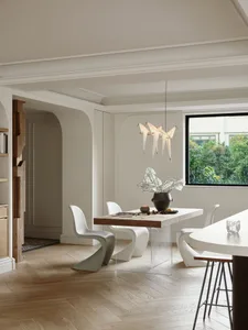 Modern dining room with metal chairs, glass table, and wooden floor.