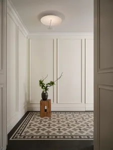 Minimalist entryway featuring a patterned tile floor and a small wooden stool with a vase on top.