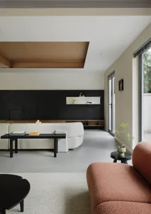A modern living room with concrete flooring, wood-paneled accent wall, and soft upholstered sofas.