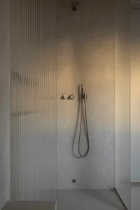 A modern minimalist bathroom with concrete walls and a walk-in shower.