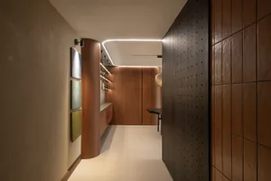 A minimalist entryway featuring sleek wooden surfaces and linear lighting.