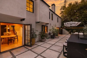 An inviting outdoor space with concrete pavers, a wooden dining table, and a cozy patio setting.