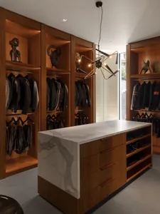 Modern walk-in closet featuring wooden shelves, marble countertop, and hanging jackets.
