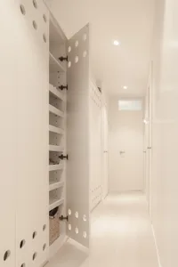 A modern hallway with white walls, a walkway intersection, and a wardrobe storage unit.