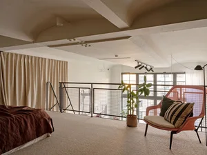 A minimalist bedroom with concrete floors, a wooden bed frame, and industrial-style decor.
