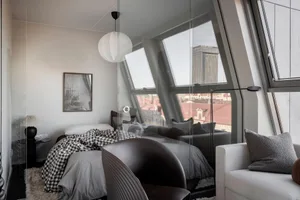 An industrial-style bedroom with mixed materials, featuring a window overlooking a cityscape.