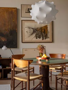 An industrial-style dining room features wooden furniture and a modern pendant light, with framed artwork on the wall.