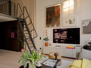 A modern industrial loft apartment featuring a minimalist design, with a metal staircase and a wooden floor.