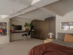 A minimalist bedroom with neutral-toned materials and a modern desk setup.