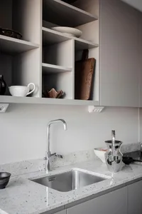 A modern, minimalist kitchen featuring a concrete countertop, designed for functionality and aesthetic appeal.